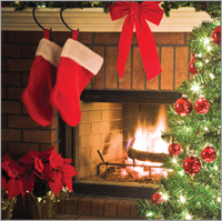 Photo of two red stockings with white trim along their tops hanging in front of a beautiful wood burning fireplace which sits just behind a beautifully decorated Christmas tree to the right, and two large Poinsettas in pots to the left. 